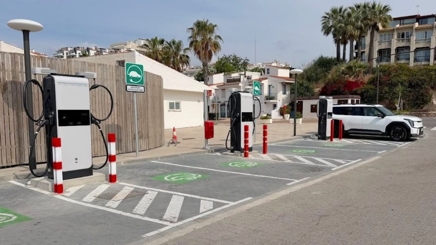 An electric vehicle charging station with two chargers and a parked white SUV in a modern parking area.