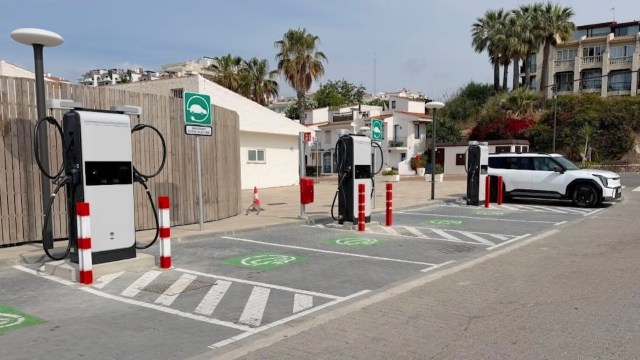 An electric vehicle charging station with two chargers and a parked white SUV in a modern parking area.