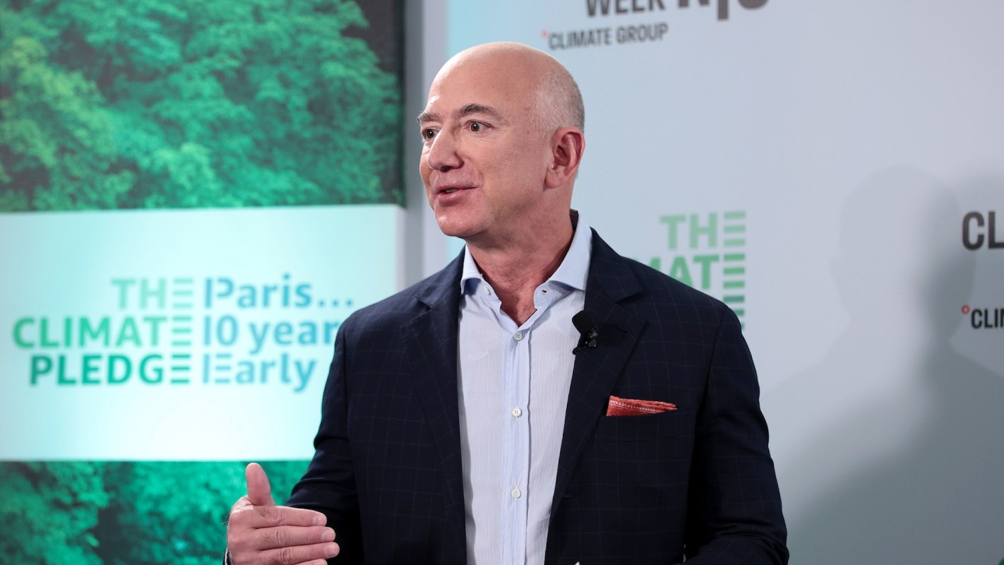 Jeff Bezos speaks at an event promoting the Paris Climate Pledge, with greenery in the background.