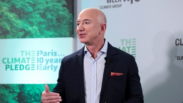 Jeff Bezos speaks at an event promoting the Paris Climate Pledge, with greenery in the background.