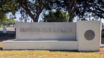 A sign for California State University surrounded by trees and greenery.