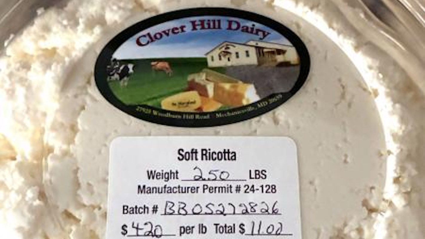 A container of soft ricotta cheese with a label displaying weight, price, and producer information.