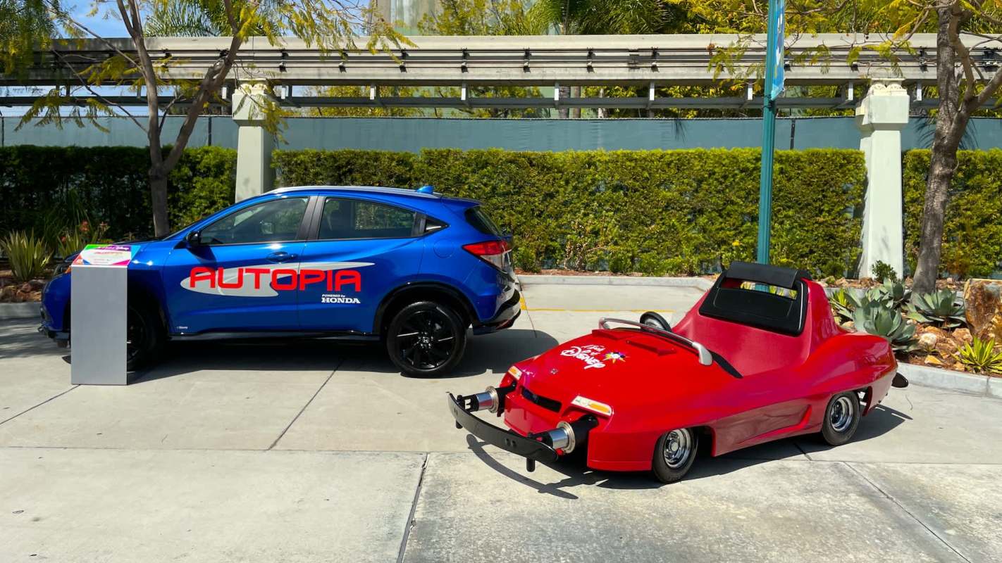 A blue SUV and a small red ride-on car parked side by side outdoors.