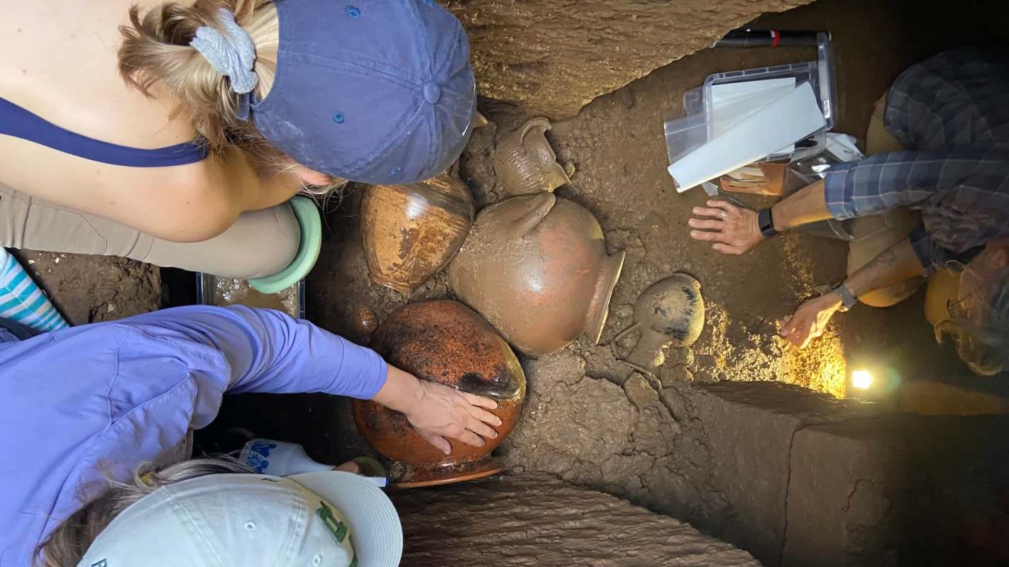 Archaeologists examining ancient pottery at an excavation site.