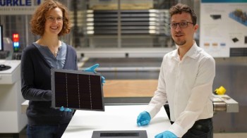 A woman and a man stand in a lab, presenting a solar panel.
