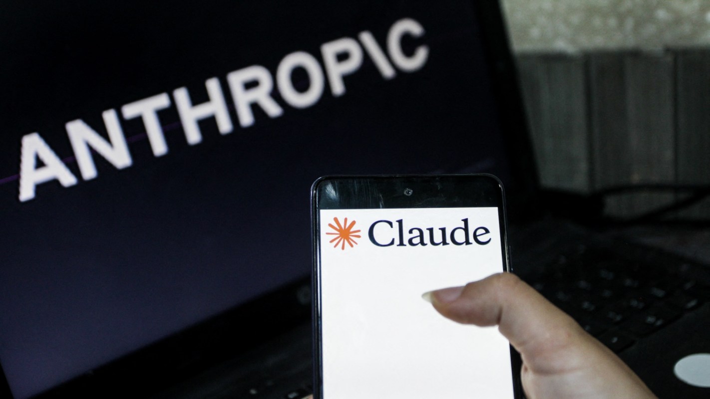 A person holding a smartphone displaying the "Claude" logo, with the word "ANTHROPIC" in the background on a laptop screen.