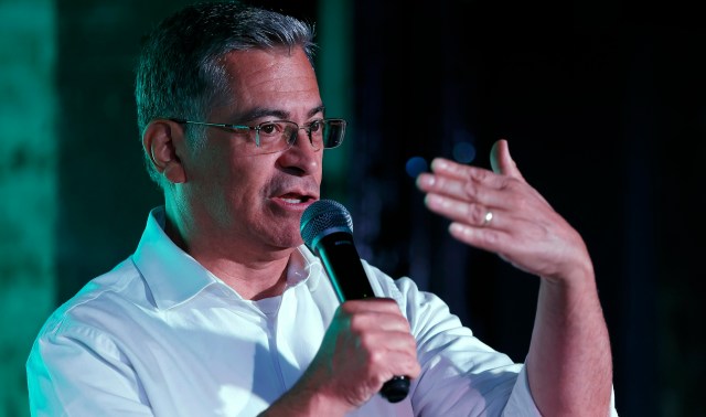 California Democratic gubernatorial candidate Xavier Becerra, in a white shirt, speaks into a microphone.