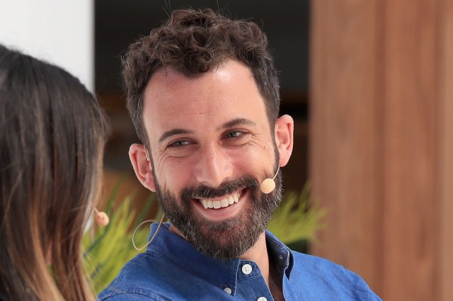 Shein founder Michael Preysman, smiling at someone seated next to him at a media event.