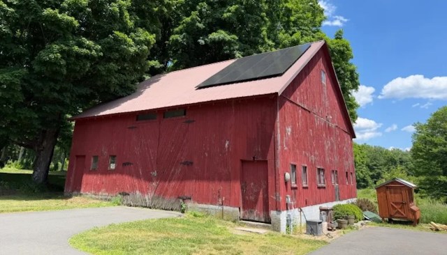 A red barn with solar panels in a rural area.