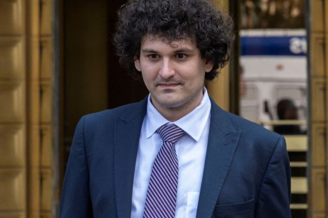 Sam Bankman-Fried stands outside a building, looking ahead.