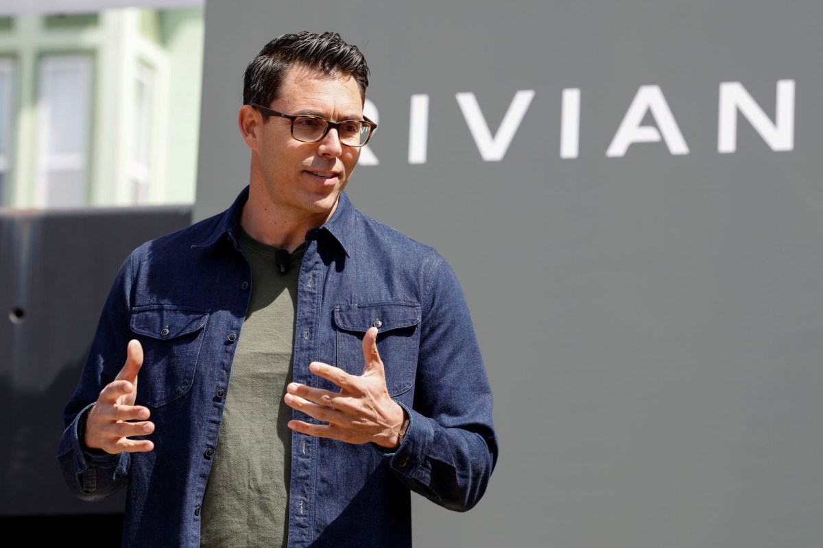 RJ Scaringe speaking in front of a Rivian logo.