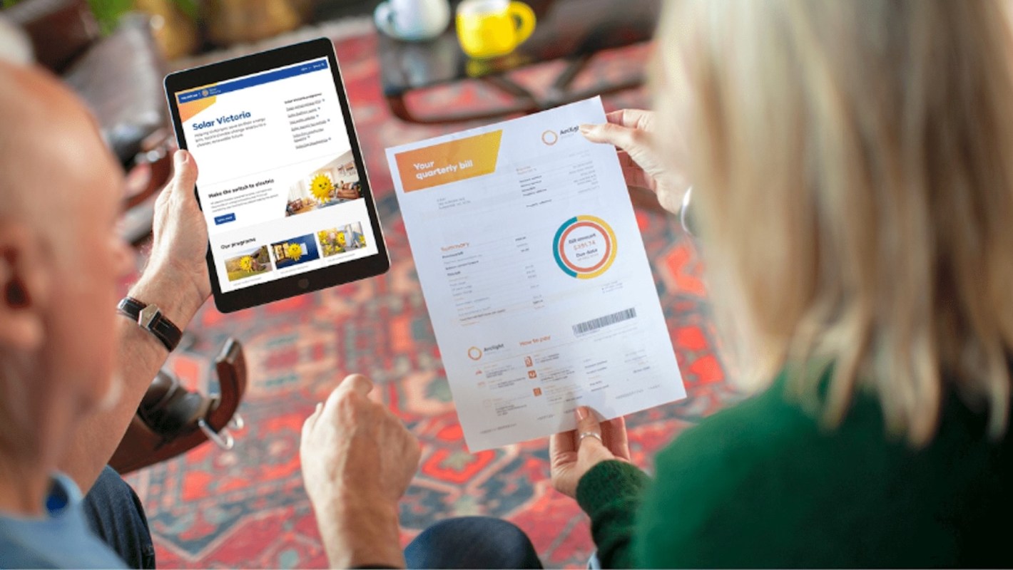 A couple reviews a quarterly bill while looking at a solar energy website on a tablet.