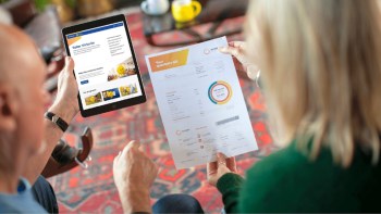 A couple reviews a quarterly bill while looking at a solar energy website on a tablet.