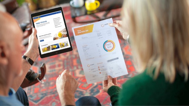 A couple reviews a quarterly bill while looking at a solar energy website on a tablet.