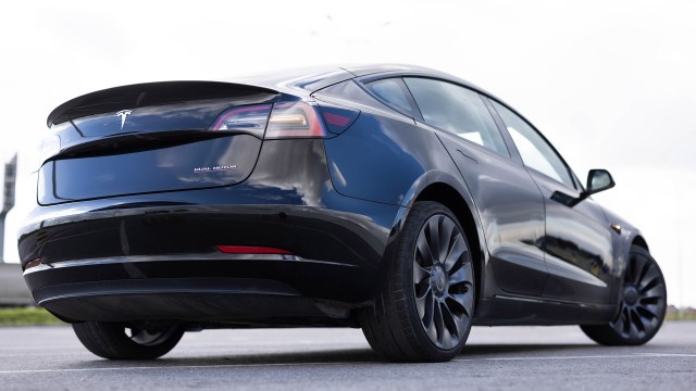 A black Tesla Model 3 viewed from the rear with a visible dual motor badge and sleek design.