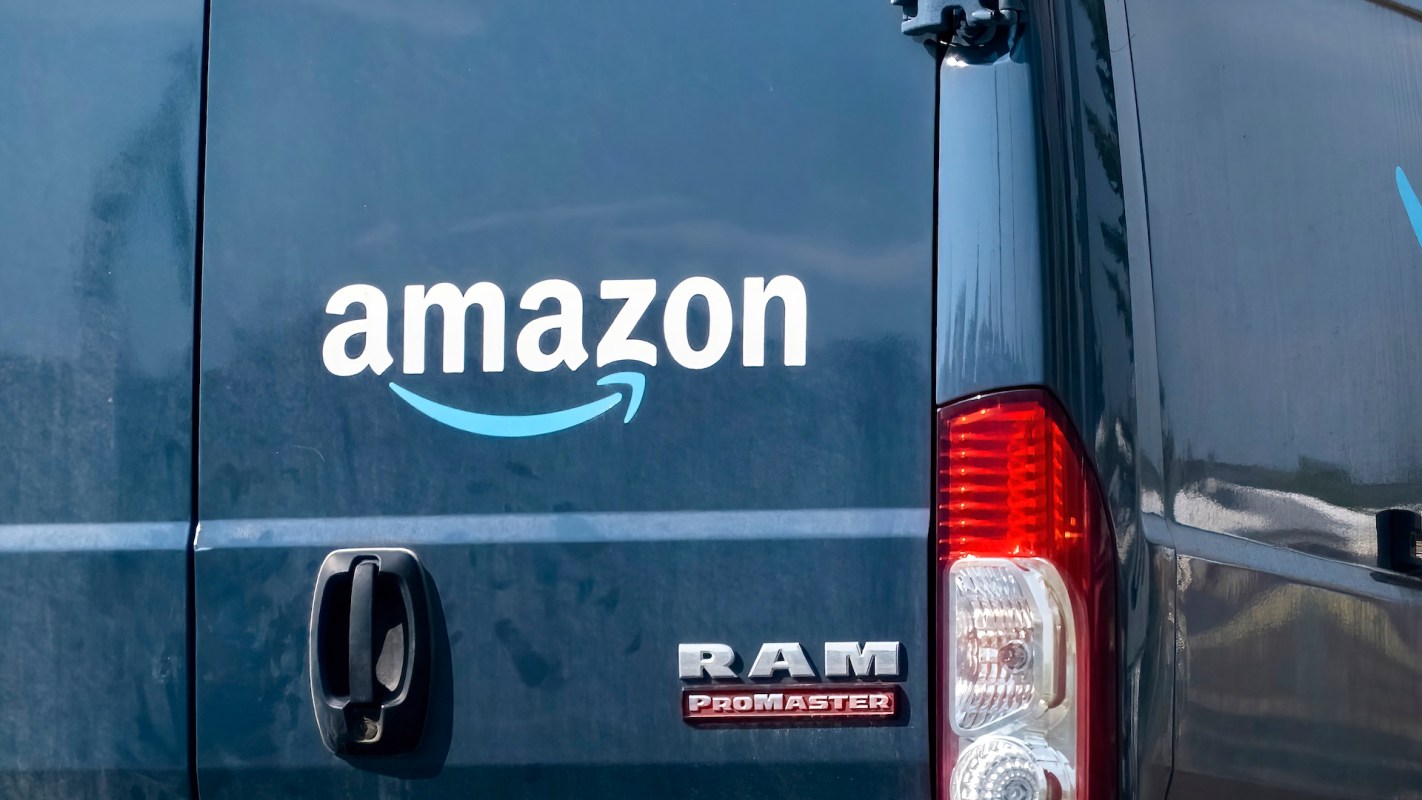 A close-up view of a blue van featuring the Amazon logo and a RAM Promaster badge.