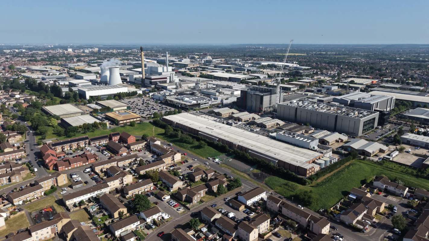 An aerial view of an industrial area with factories, warehouses, and residential buildings under a clear blue sky.