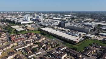 An aerial view of an industrial area with factories, warehouses, and residential buildings under a clear blue sky.