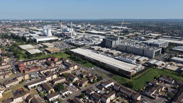 An aerial view of an industrial area with factories, warehouses, and residential buildings under a clear blue sky.