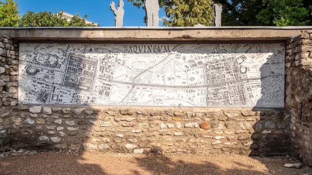 A historical map mural depicting the ancient city layout of Aquincum on a stone wall.