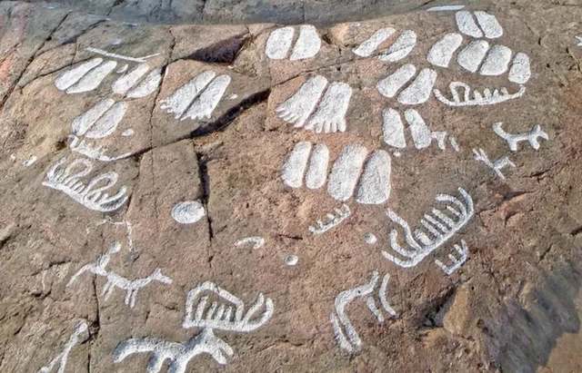 Ancient rock carvings depicting various symbols, including footprints, animals, and geometric shapes.
