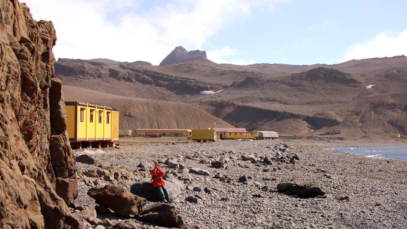 A rocky Antarctic beach with yellow trailers.