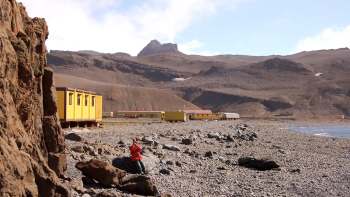 A rocky Antarctic beach with yellow trailers.