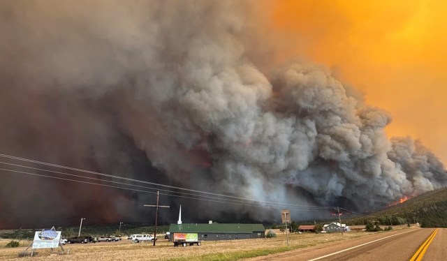 A thick plume of smoke rises ominously over a rural community.