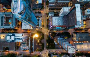 Aerial view of an urban intersection surrounded by tall buildings and city streets illuminated at dusk.