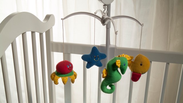 A colorful mobile featuring plush sea creatures hanging above a crib with soft lighting in the background.