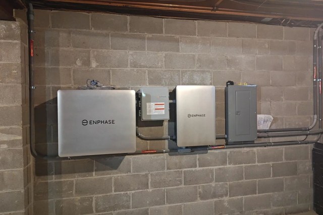 A wall of a basement displaying solar energy equipment and electrical panels.