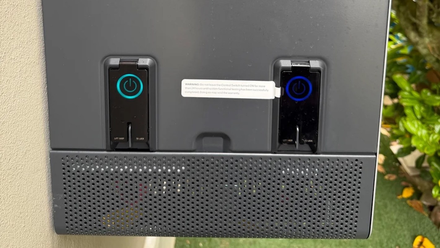 A close-up of a control panel with two power buttons and a warning label mounted on a textured surface.