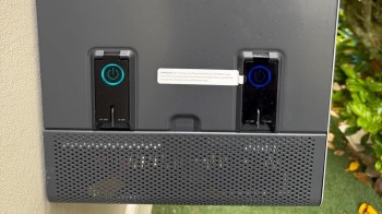 A close-up of a control panel with two power buttons and a warning label mounted on a textured surface.