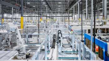 A modern automated factory interior with robotic arms and conveyor systems arranged in a spacious layout.