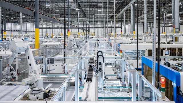 A modern automated factory interior with robotic arms and conveyor systems arranged in a spacious layout.