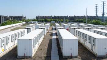 Aerial view of a cluster of white battery storage units in rows on a sunny day.