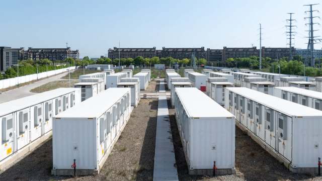 Aerial view of a cluster of white battery storage units in rows on a sunny day.