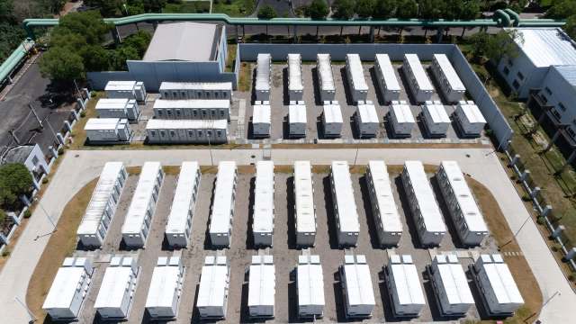 An aerial view of a neatly organized cluster of white shipping containers on a gravel lot.