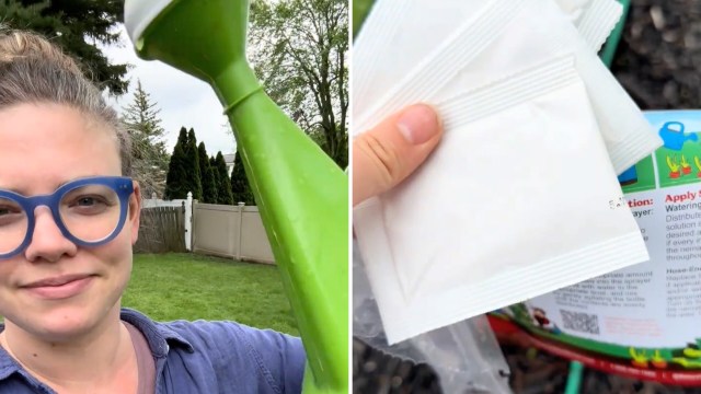 A woman with glasses holds a green watering can in a backyard, with packets of seeds visible in her other hand.