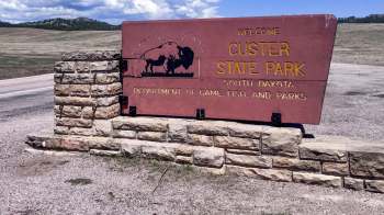 Welcome sign with stone base for Custer State Park in South Dakota, featuring a bison silhouette.