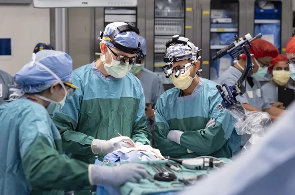 Surgeons in scrubs perform a procedure in an operating room.