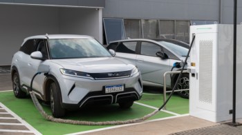Two electric cars parked at a charging station, with one vehicle connected to the charger.
