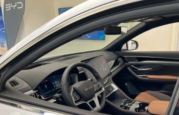 A modern BYD car interior featuring a large digital display and a sporty steering wheel with leather accents.