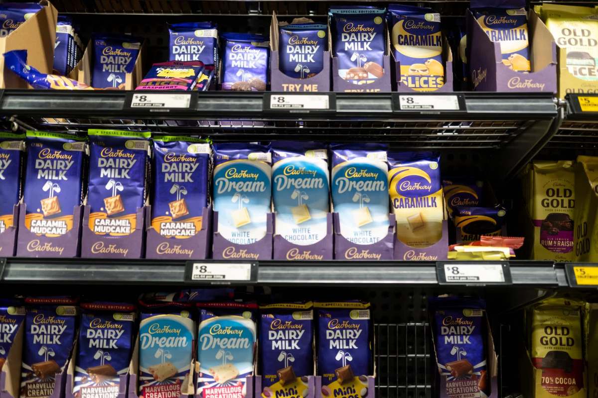 A shelf filled with various Cadbury chocolate bars, including Dairy Milk and Dream varieties.