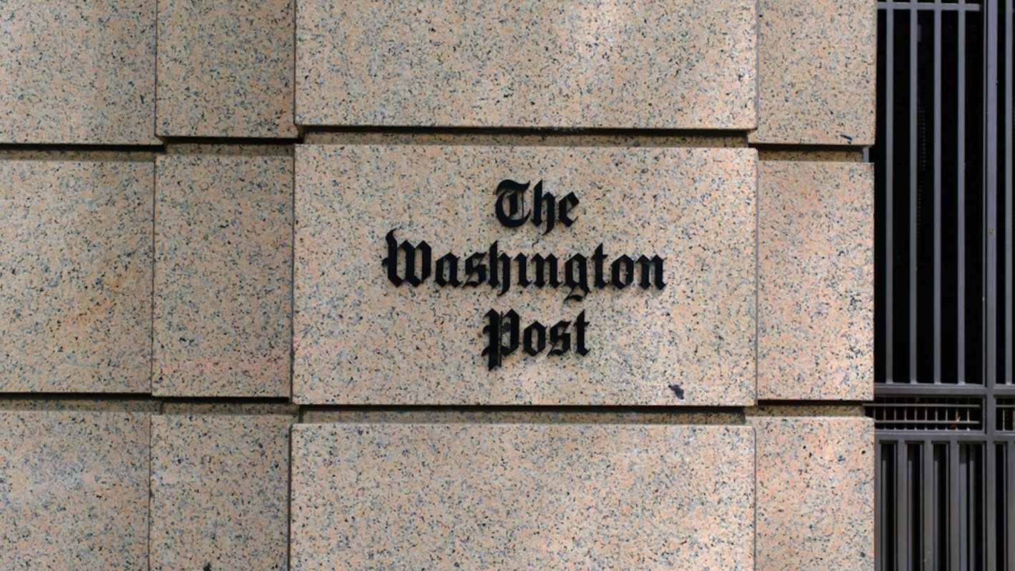 The exterior wall of a building features the sign for "The Washington Post" in bold lettering.