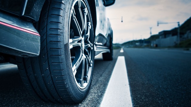 A close-up view of a car tire resting on an empty road with a blurred background.