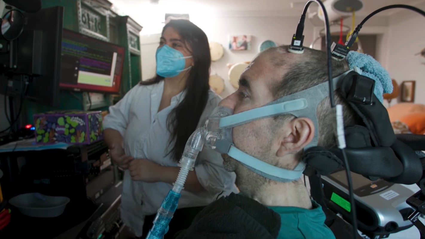 A man using a breathing apparatus while a woman in a mask monitors a computer screen.