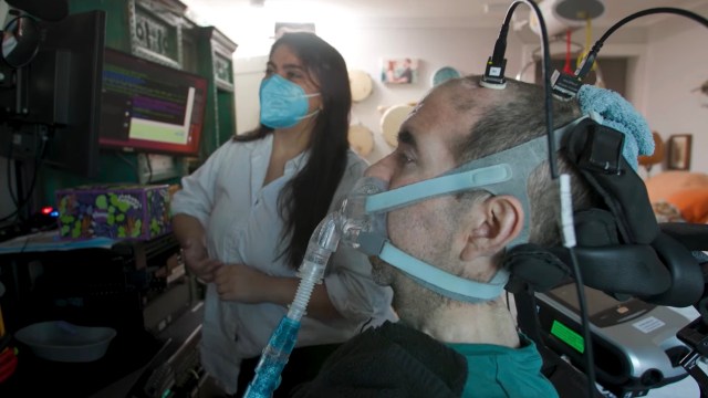 A man using a breathing apparatus while a woman in a mask monitors a computer screen.