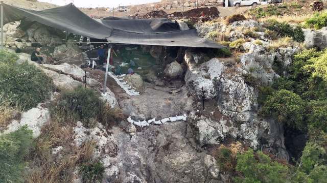 An excavation site amid vegetation on a rocky hillside.