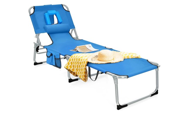 A blue lounge chair with a headrest, a straw hat, and a yellow blanket draped over it.